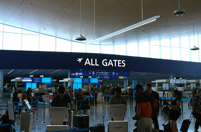 Plane passengers waiting in line at airport security control, illustrating entitled passenger cutting cue situation.